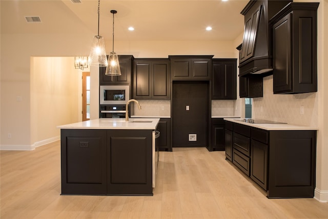 kitchen with stainless steel appliances, a sink, visible vents, light countertops, and custom exhaust hood