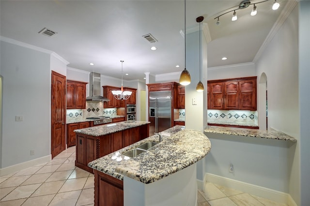 kitchen with sink, appliances with stainless steel finishes, an island with sink, pendant lighting, and wall chimney range hood