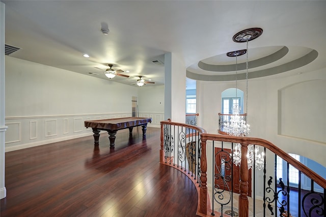 rec room with a notable chandelier, dark hardwood / wood-style flooring, and a tray ceiling