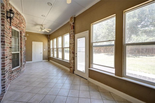 unfurnished sunroom featuring ceiling fan