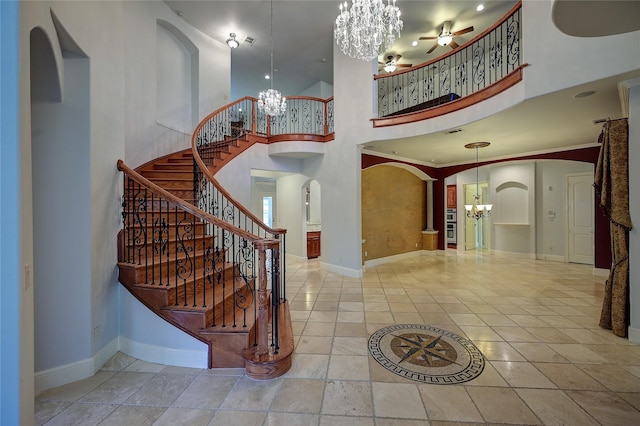 entrance foyer with a high ceiling, crown molding, and ceiling fan with notable chandelier