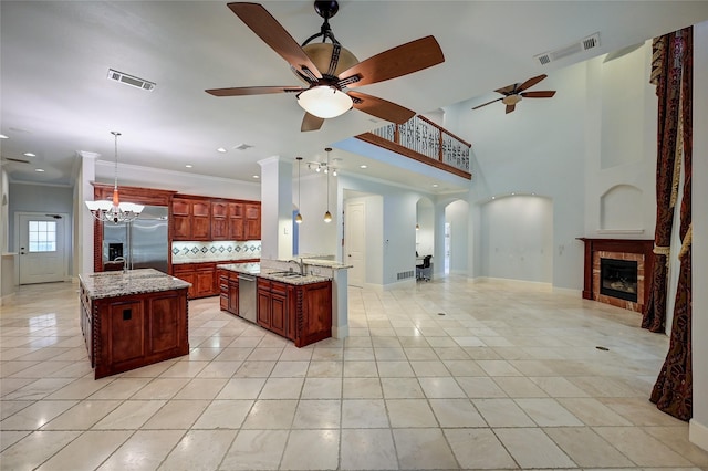 kitchen featuring hanging light fixtures, appliances with stainless steel finishes, sink, and a center island with sink