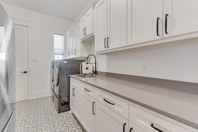 washroom with sink, washing machine and dryer, and cabinets