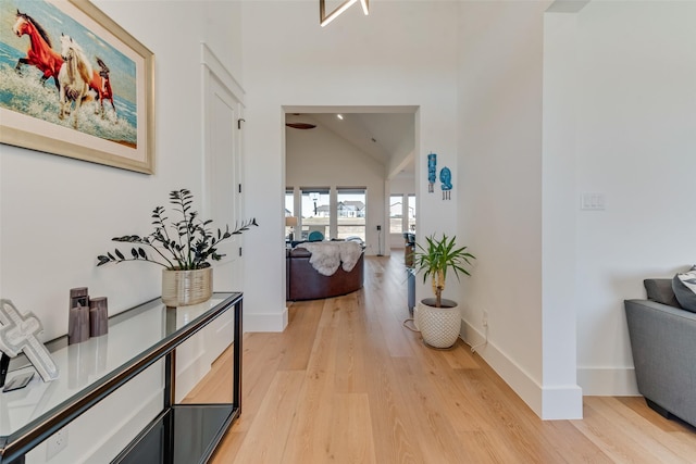 hall with light hardwood / wood-style flooring and high vaulted ceiling