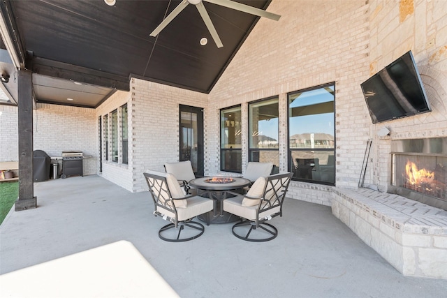 view of patio with an outdoor brick fireplace, a grill, ceiling fan, and an outdoor fire pit