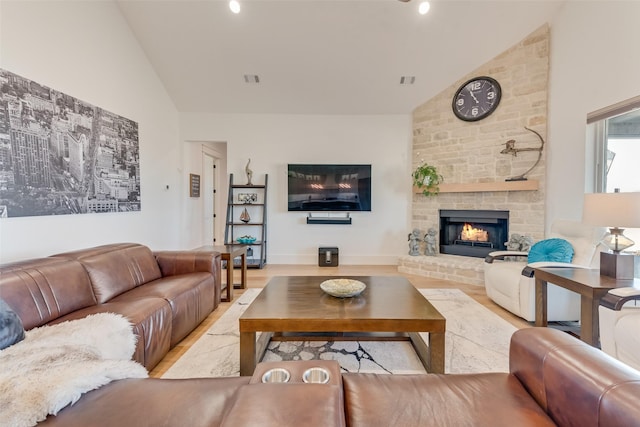 living room with a brick fireplace, light hardwood / wood-style flooring, and high vaulted ceiling