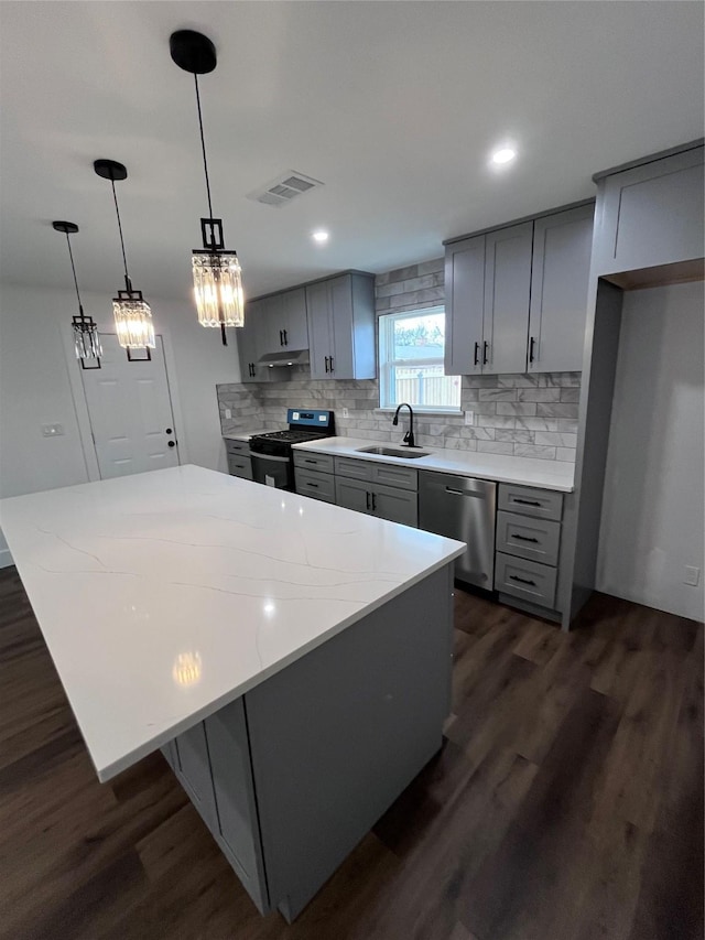 kitchen with sink, gas stove, decorative light fixtures, a center island, and stainless steel dishwasher