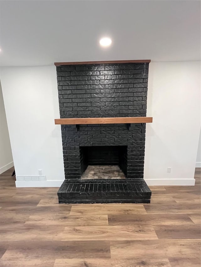 interior details featuring hardwood / wood-style flooring and a brick fireplace