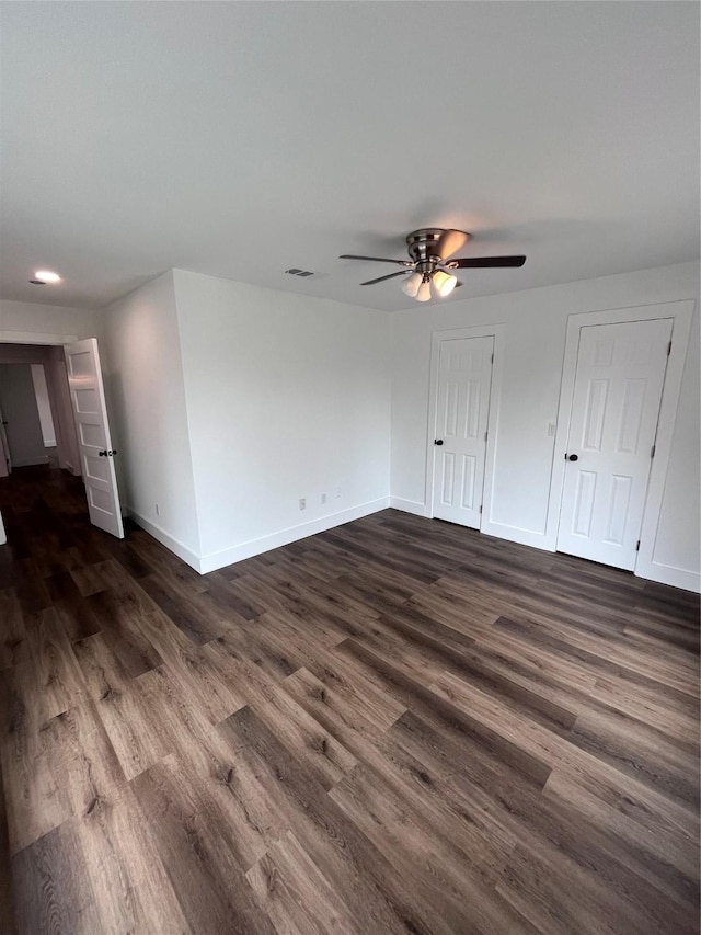 empty room with ceiling fan and dark hardwood / wood-style flooring