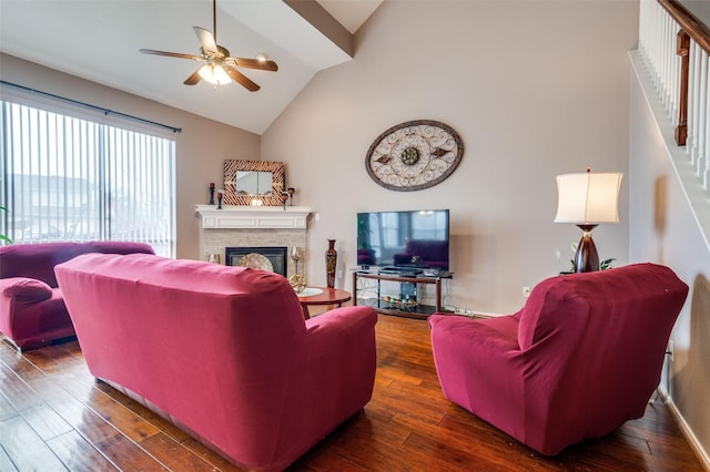 living area featuring high vaulted ceiling, dark wood-style flooring, ceiling fan, and a stone fireplace