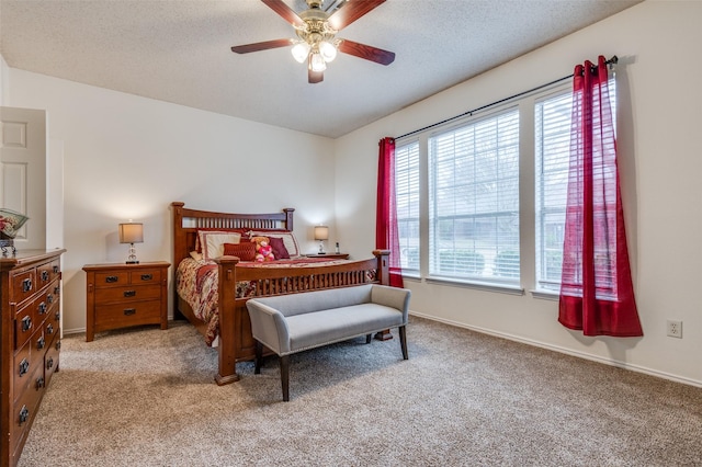 bedroom featuring light carpet, a textured ceiling, a ceiling fan, and baseboards