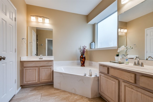 bathroom with two vanities, a sink, and a bath