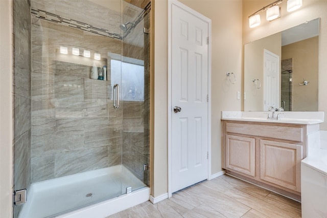 full bathroom featuring baseboards, a shower stall, and vanity