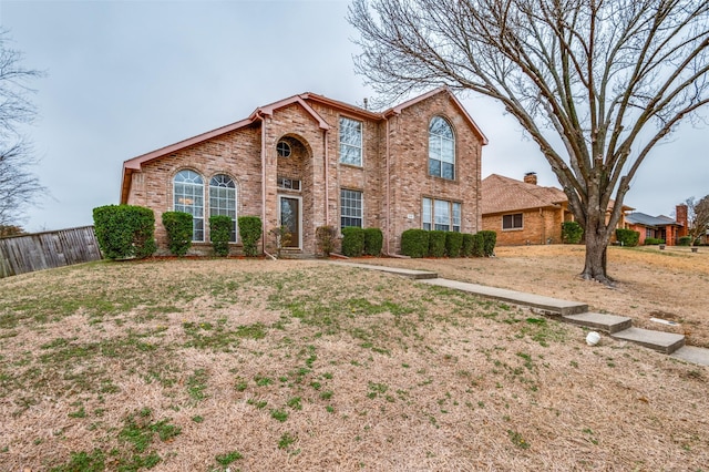 traditional-style home featuring brick siding and fence