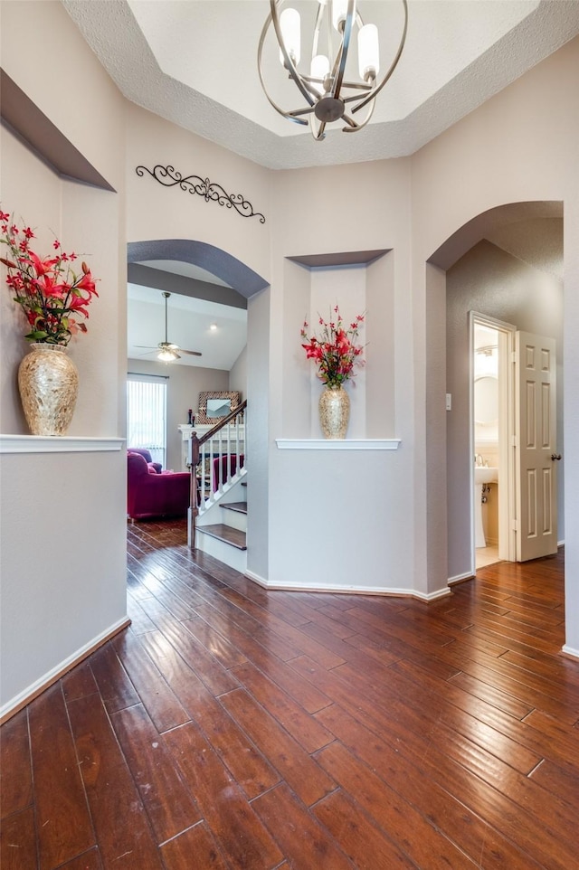 interior space with arched walkways, stairs, hardwood / wood-style flooring, and baseboards