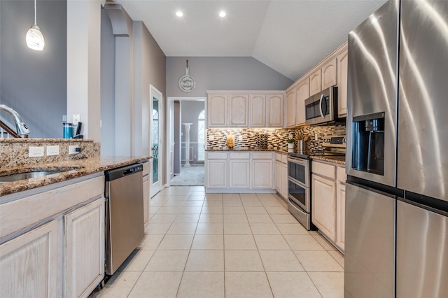 kitchen featuring light tile patterned floors, tasteful backsplash, stone countertops, stainless steel appliances, and a sink