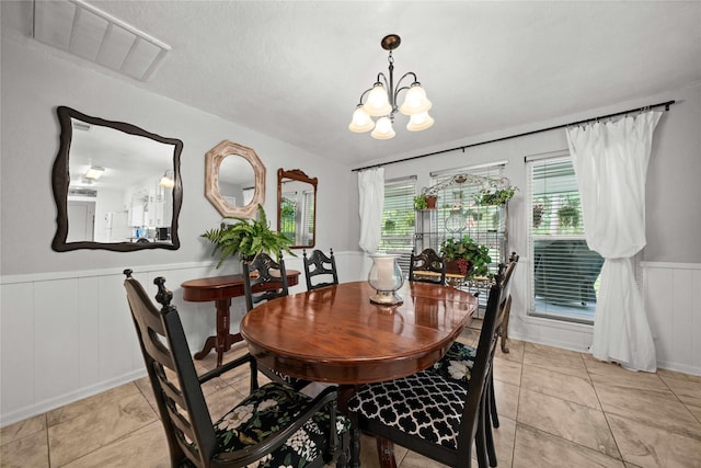 dining area with light tile patterned floors, a textured ceiling, and a chandelier