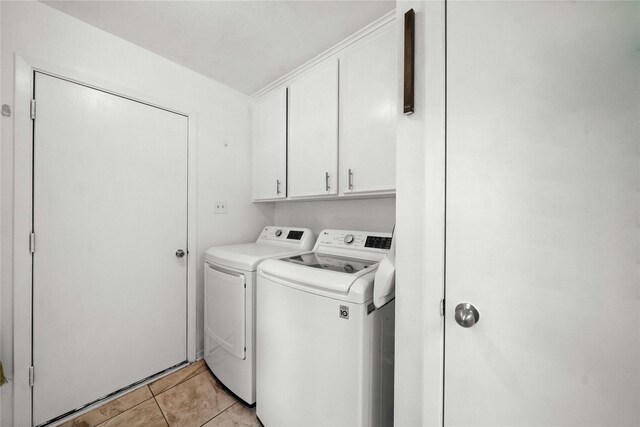 clothes washing area with cabinets, light tile patterned floors, and independent washer and dryer