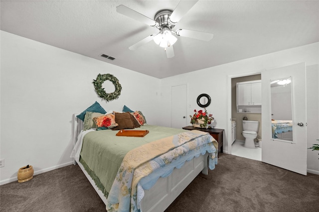 bedroom featuring ensuite bath, a textured ceiling, ceiling fan, and dark colored carpet