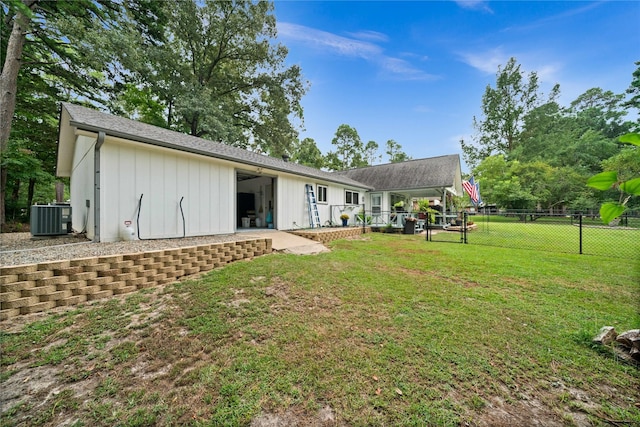 rear view of property with cooling unit and a yard