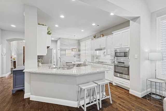 kitchen with stainless steel appliances, white cabinetry, a kitchen bar, and kitchen peninsula