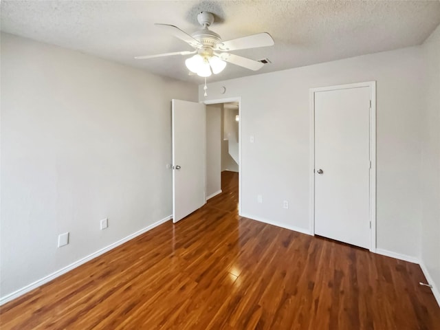 unfurnished bedroom with ceiling fan, dark wood-type flooring, and a textured ceiling