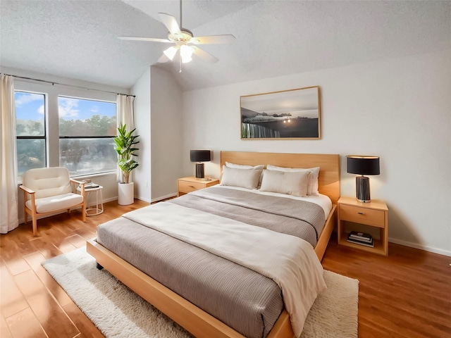 bedroom featuring ceiling fan, lofted ceiling, hardwood / wood-style floors, and a textured ceiling