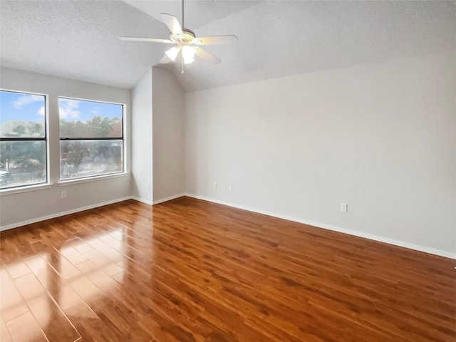 empty room featuring a textured ceiling, vaulted ceiling, dark hardwood / wood-style floors, and ceiling fan