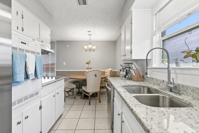 kitchen with light tile patterned floors, decorative light fixtures, sink, and white cabinets