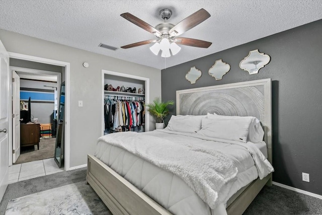 bedroom with light carpet, ceiling fan, a closet, and a textured ceiling