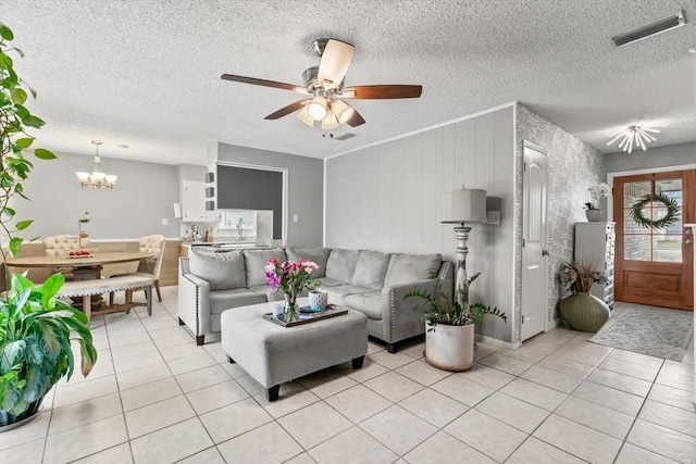 living room featuring ceiling fan with notable chandelier, light tile patterned floors, and a textured ceiling