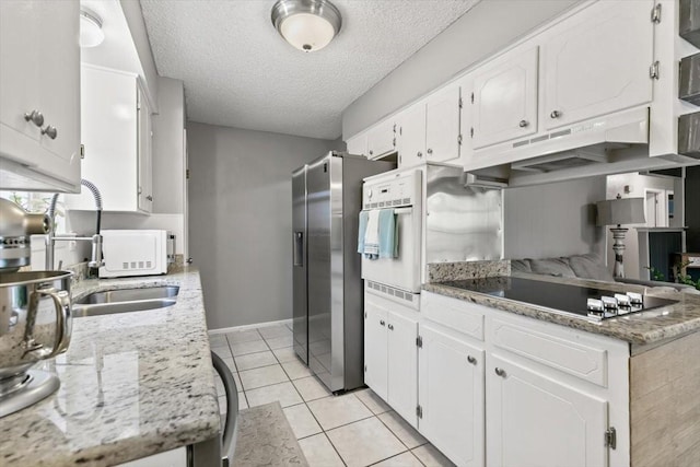 kitchen featuring light tile patterned flooring, white cabinetry, light stone counters, stainless steel fridge with ice dispenser, and black electric cooktop