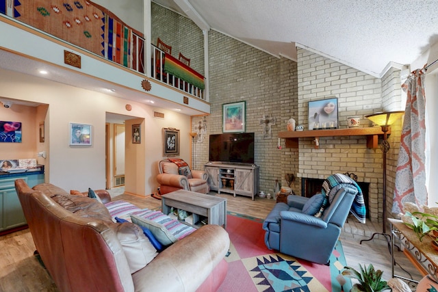 living area featuring a brick fireplace, visible vents, a textured ceiling, light wood-style floors, and high vaulted ceiling