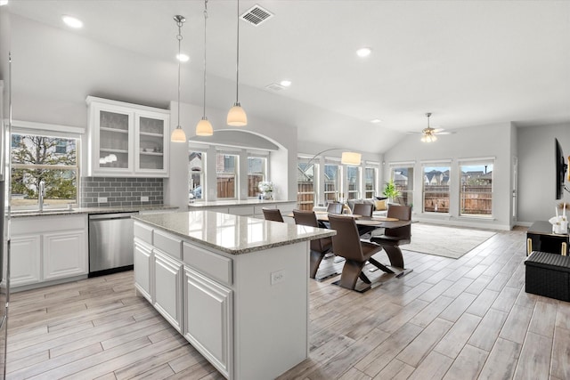 kitchen with visible vents, a sink, tasteful backsplash, stainless steel dishwasher, and open floor plan