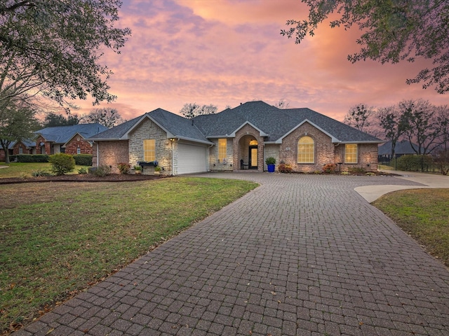 ranch-style house with a garage and a lawn