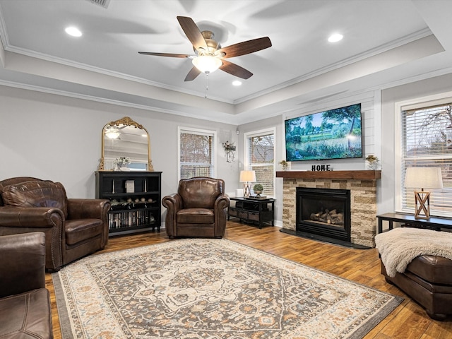 living room featuring hardwood / wood-style flooring, ornamental molding, and a raised ceiling