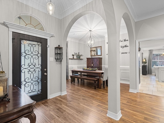 foyer entrance featuring crown molding, light hardwood / wood-style flooring, and a chandelier