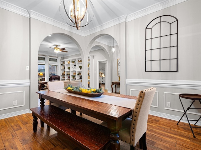 dining space featuring crown molding, ceiling fan with notable chandelier, hardwood / wood-style floors, and built in features