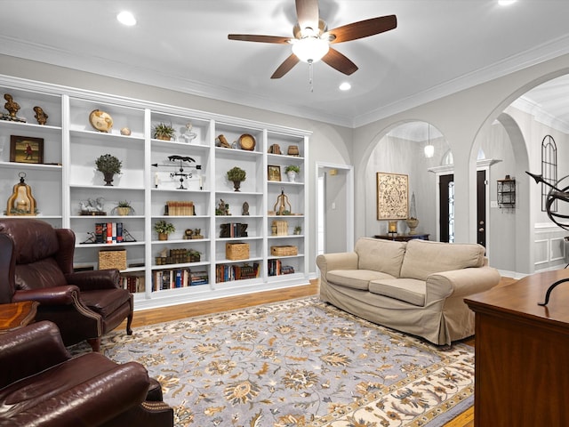 living room with light hardwood / wood-style flooring, ornamental molding, and ceiling fan