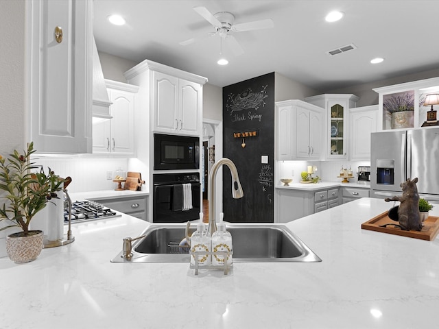 kitchen with white cabinetry, sink, ceiling fan, black appliances, and light stone countertops