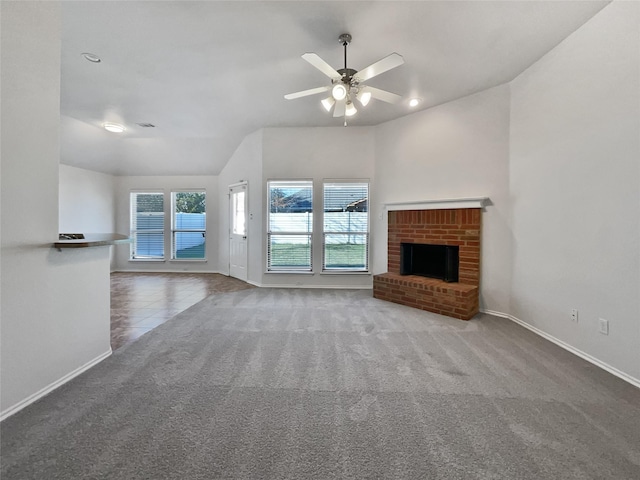 unfurnished living room featuring a brick fireplace, vaulted ceiling, ceiling fan, and carpet