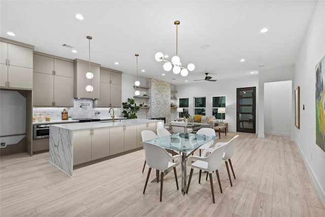 dining space with ceiling fan, a fireplace, sink, and light hardwood / wood-style floors