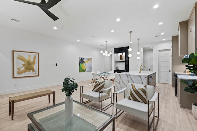 living room featuring sink, an inviting chandelier, and light wood-type flooring