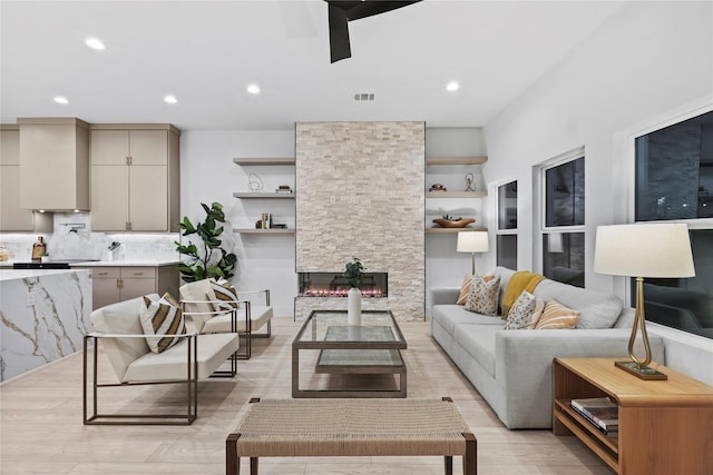 living room with a stone fireplace and light hardwood / wood-style floors