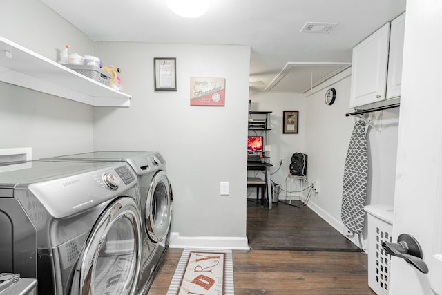 clothes washing area featuring cabinets, washing machine and dryer, and dark wood-type flooring