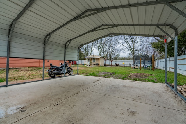 view of vehicle parking with a trampoline, a yard, and a carport