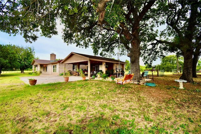 back of house with a patio and a lawn