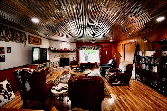 living room with a brick fireplace, wood ceiling, wood-type flooring, and ceiling fan