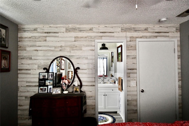 bedroom with sink, a textured ceiling, and ensuite bath