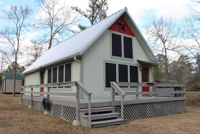 rear view of house with a shed, a lawn, and a deck